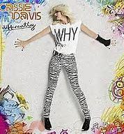 Album cover featuring a woman in zebra print pants and a t-shirt with "why" printed on it, posing dynamically against a graffiti background, surrounded by vinyl records. (CASSIE DAVIS - DIFFERENTLY CD)