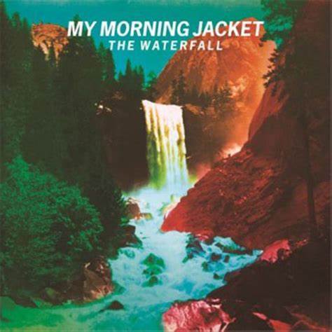Album cover of "MY MORNING JACKET - WATERFALL II (VINYL LP)," featuring an illustrated waterfall amid verdant cliffs, with sunlight casting a warm glow on the vinyl record.